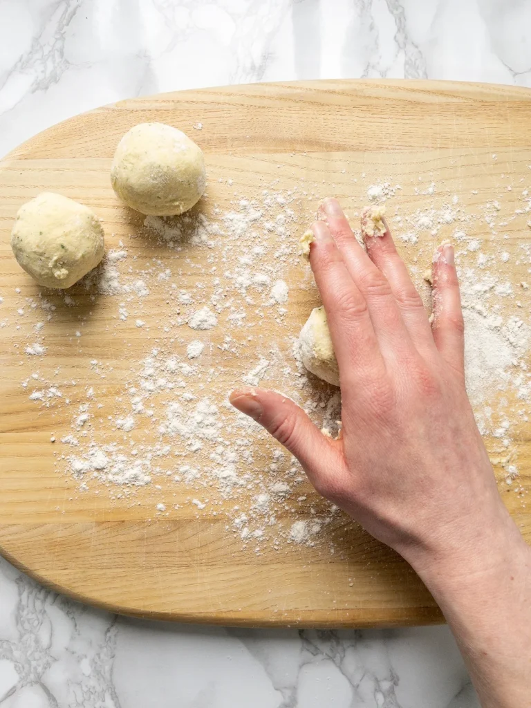 Rolling balls of dumpling mixture on a floured surface