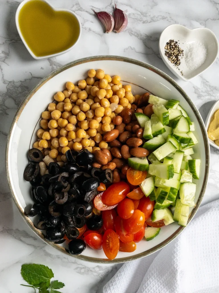 Chickpeas, borlotti beans, cannellini beans, cucumber and tomatoes for vegan bean salad. Next, add the olives.