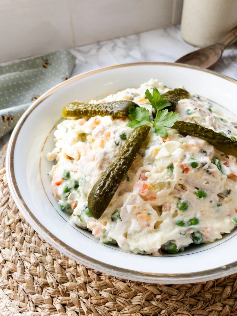 Olivier salad recipe, decorated with pickles and parsley.