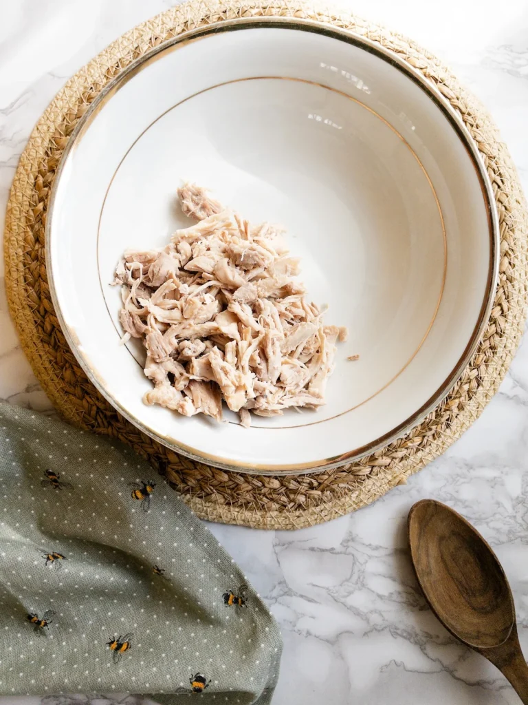 Add shredded chicken to a bowl for salad olivieh recipe.