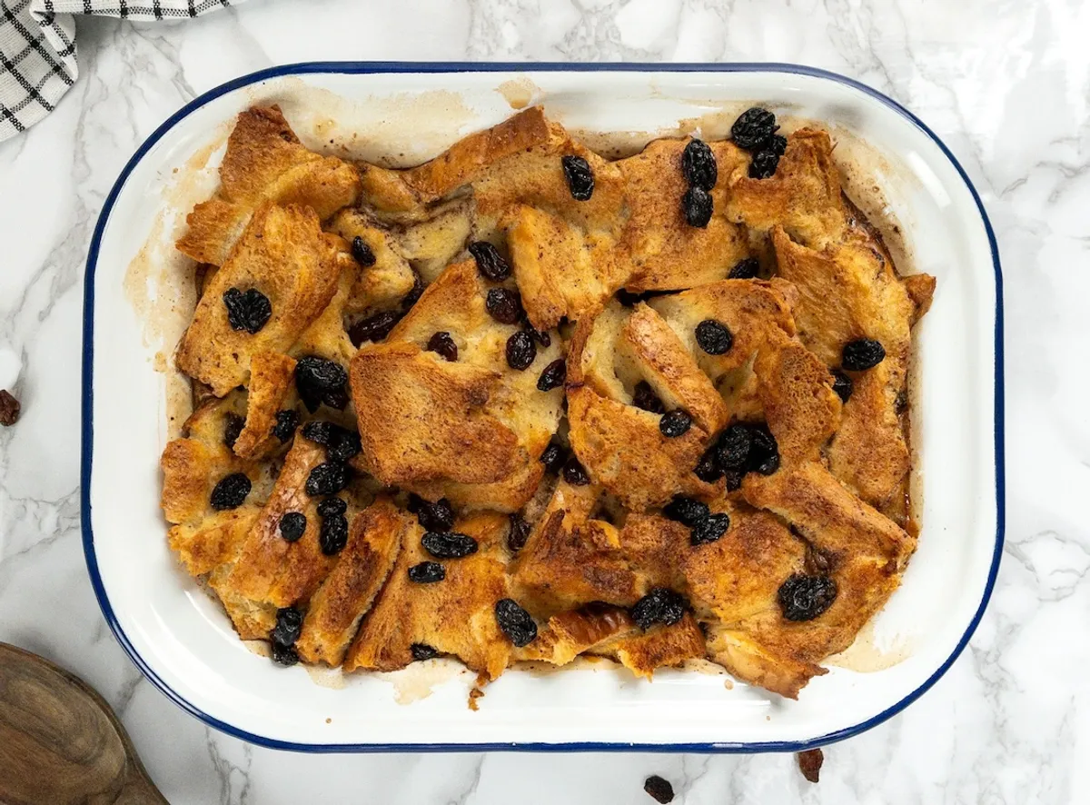 Dairy-free bread pudding recipe with golden crust and raisins, served warm.