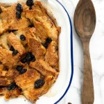 Rich dairy-free bread pudding served as a dessert, topped with raisins.