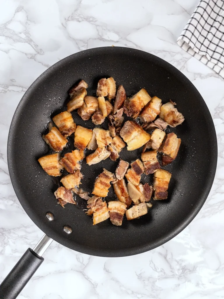 Crispy pork belly in a frying pan.