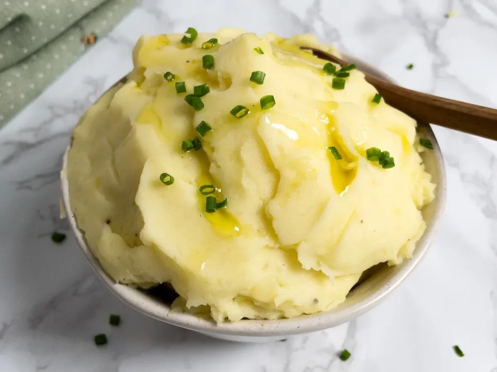 A bowl of dairy-free mashed potatoes, garnished with chives.