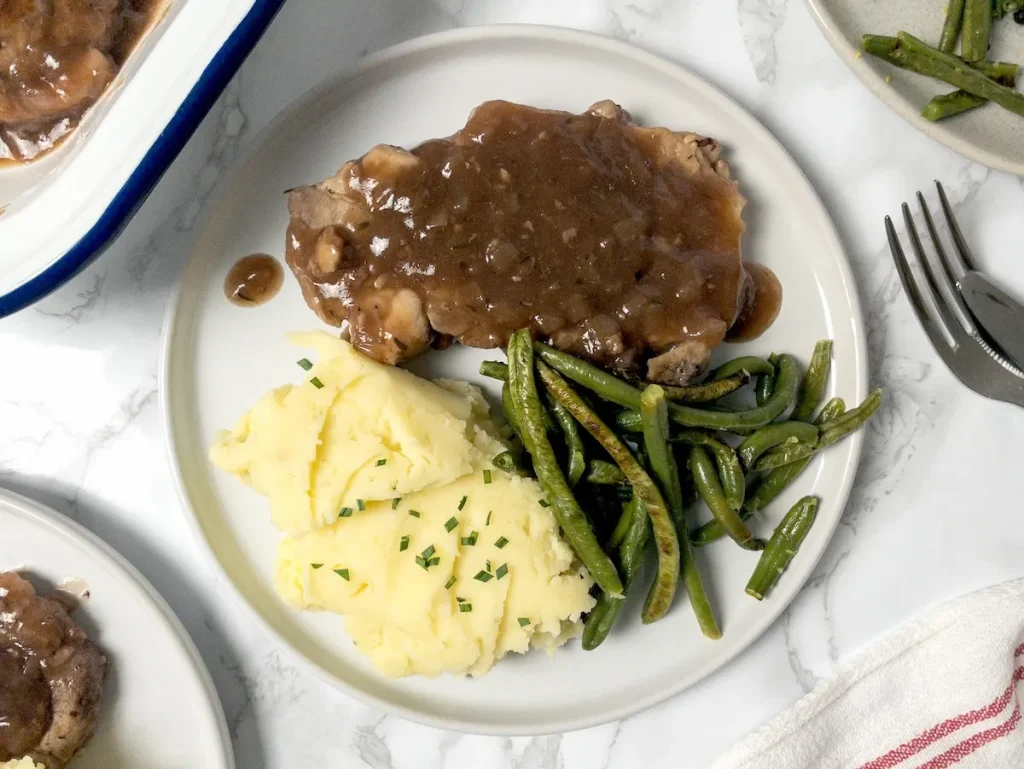 Plate with pork chops, mashed potatoes, and green beans.