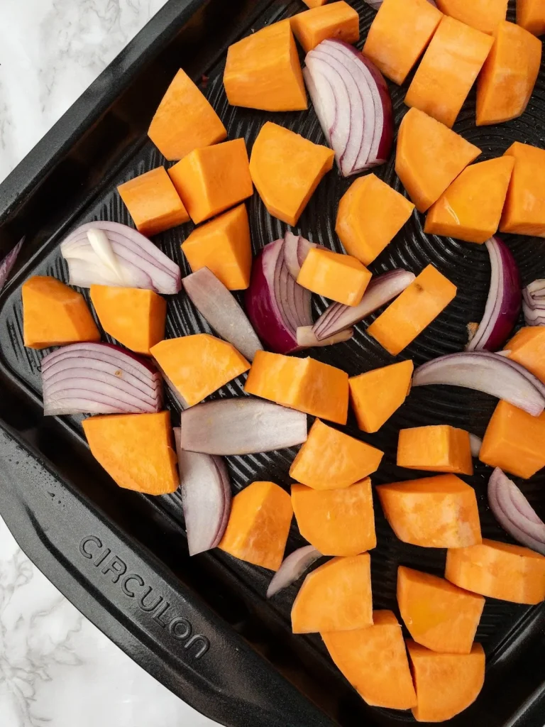 Chopped sweet potatoes and onions ready to roast for honey mustard pork chops.