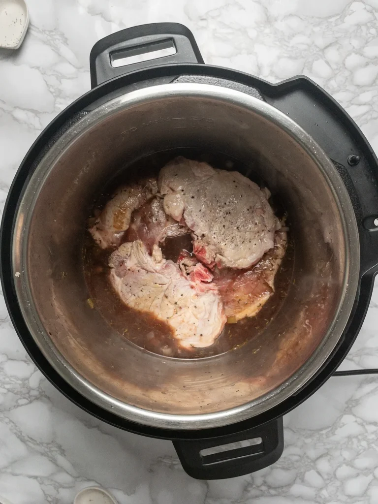 Instant Pot with seared frozen pork chops and gravy ingredients inside, ready to cook on High Pressure mode.