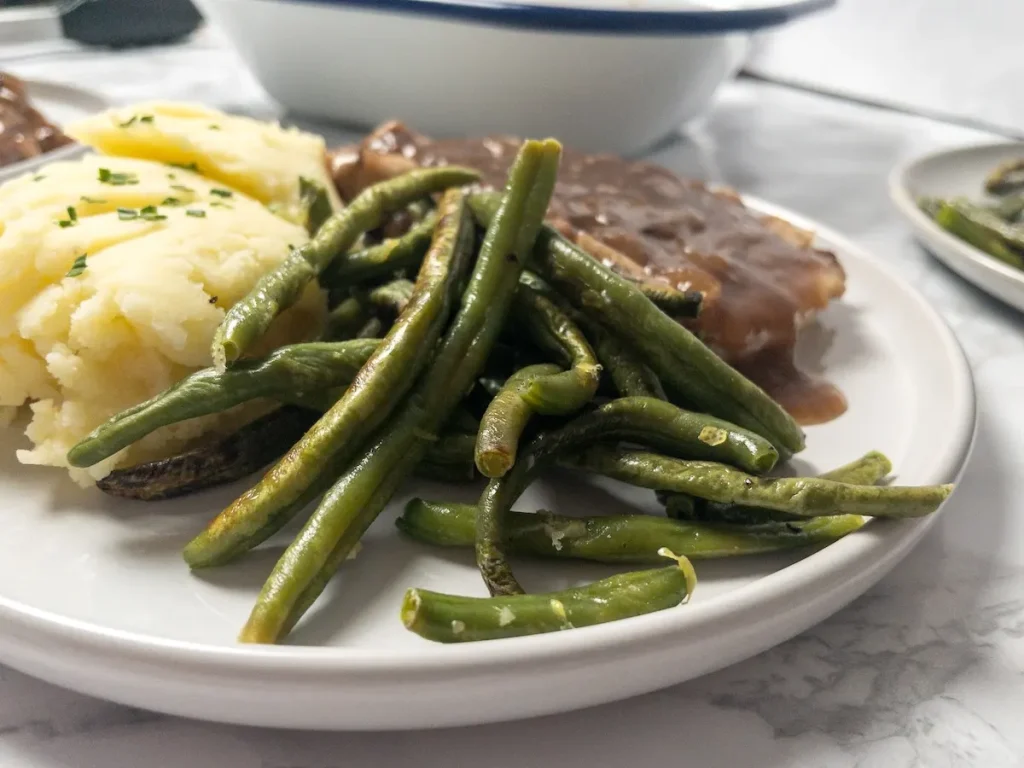 Lemon Garlic Roasted Green Beans served with mashed potatoes and pork chops.