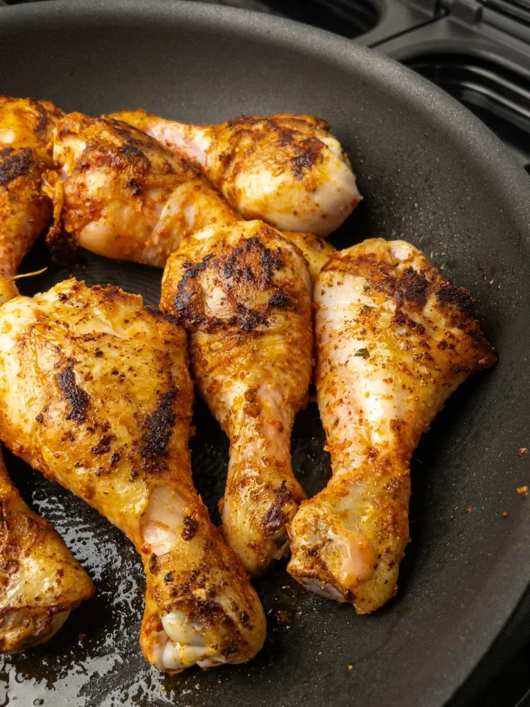 Drumsticks cooking in a skillet.