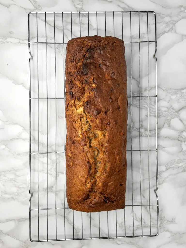 The banana bread loaf cooling on a rack after baking.