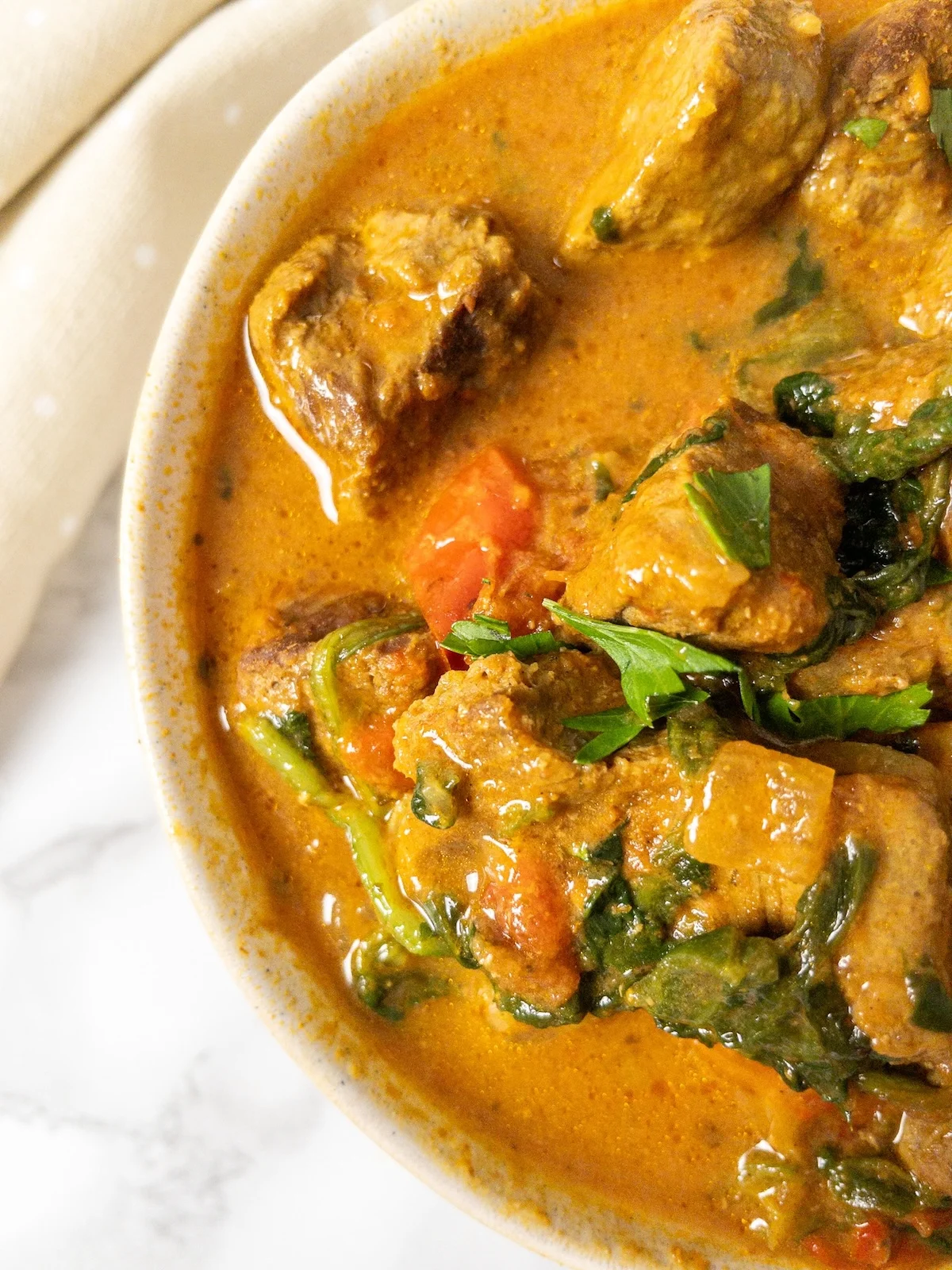 Bowl of Instant Pot beef curry with red peppers and spinach