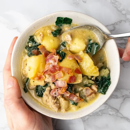 Dairy-free Zuppa Toscana in a bowl held by hands.