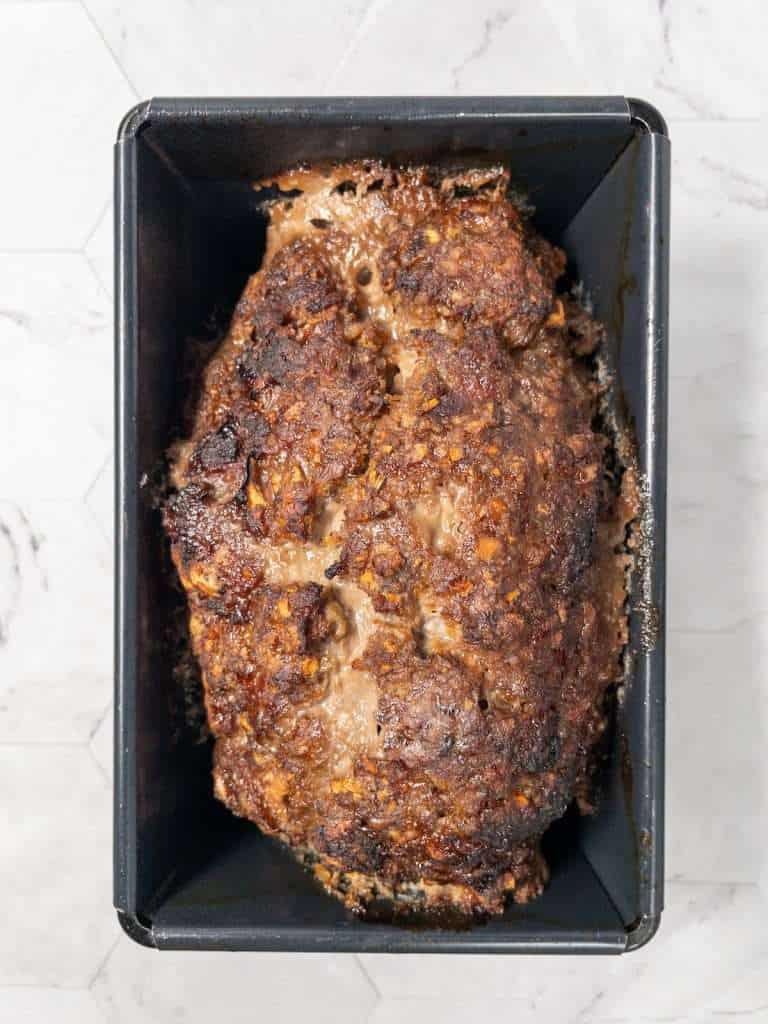 Freshly baked meatloaf in a loaf tin, golden brown and ready to serve.