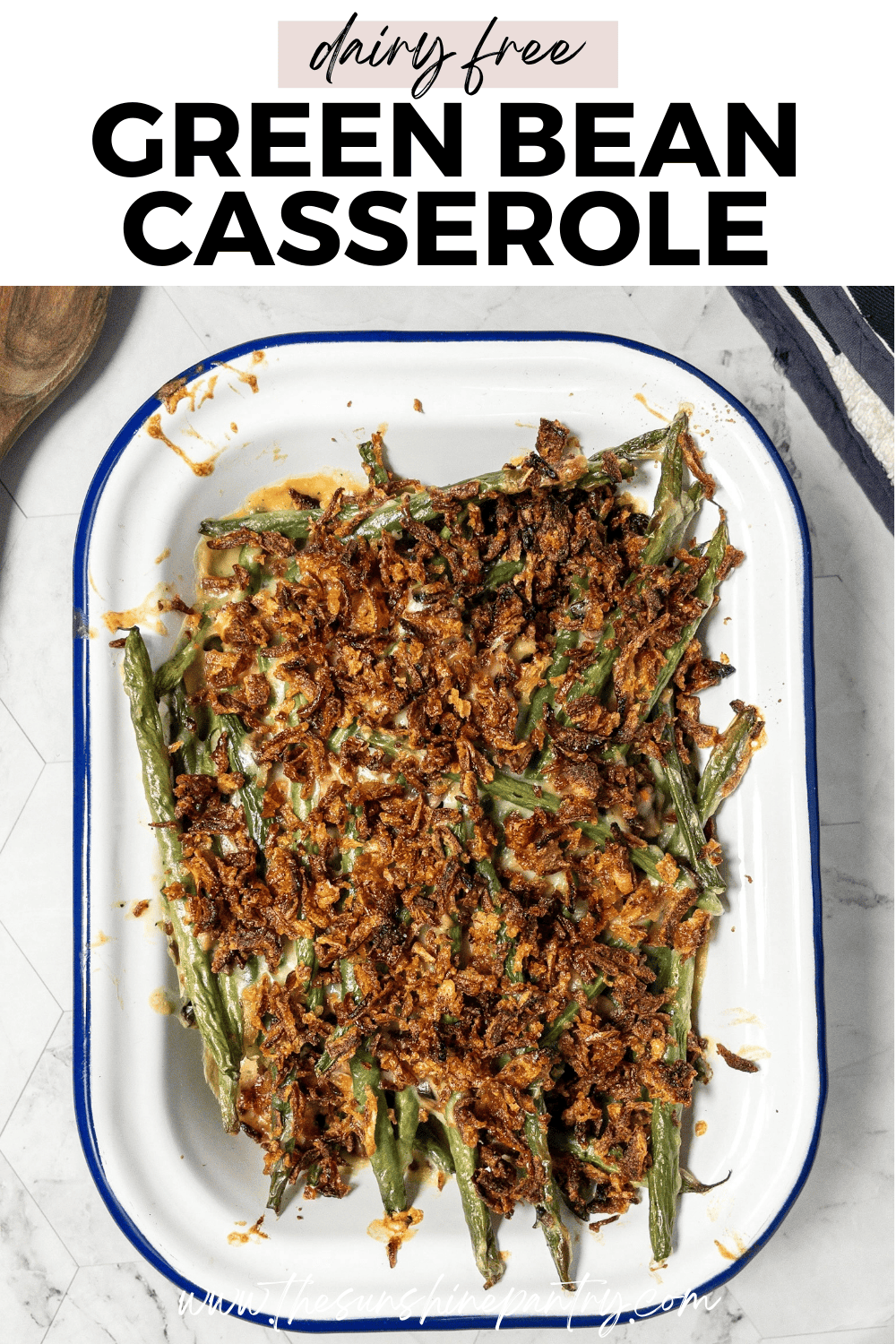 Dairy free green bean casserole topped with crispy onions, served in a white baking dish on a holiday table.