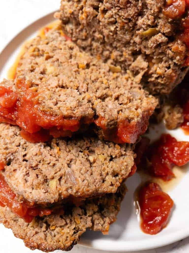 Baked dairy free meatloaf sliced and served with tomato glaze.