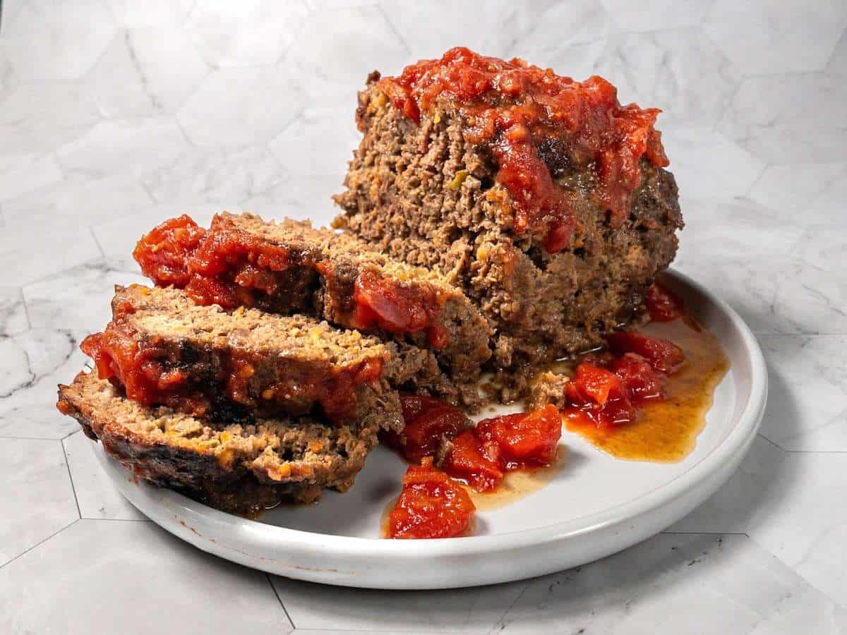 Sliced easy meatloaf recipe without milk served on a plate with tomato glaze.