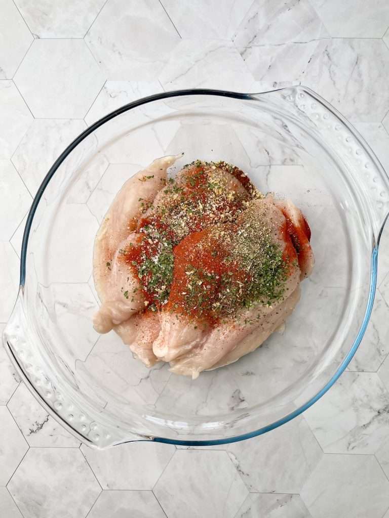 A bowl of chicken breasts  with the spice mix on top.