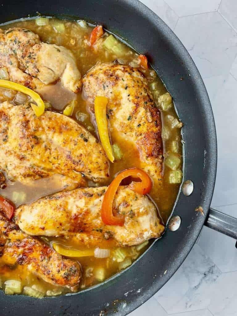 A pan of cajun chicken and vegetables with the stock and Worcester sauce added in, ready to cook.