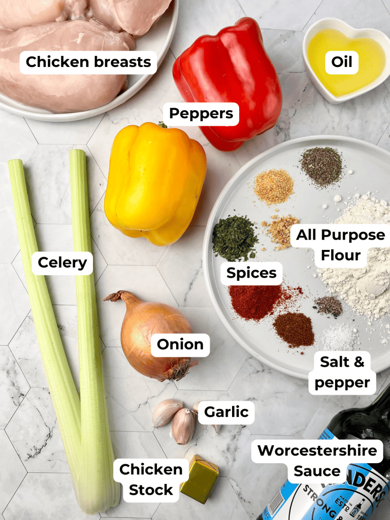 Ingredients for Cajun Smothered Chicken recipe, including chicken breasts, celery, peppers, onion and cajun spice mix.