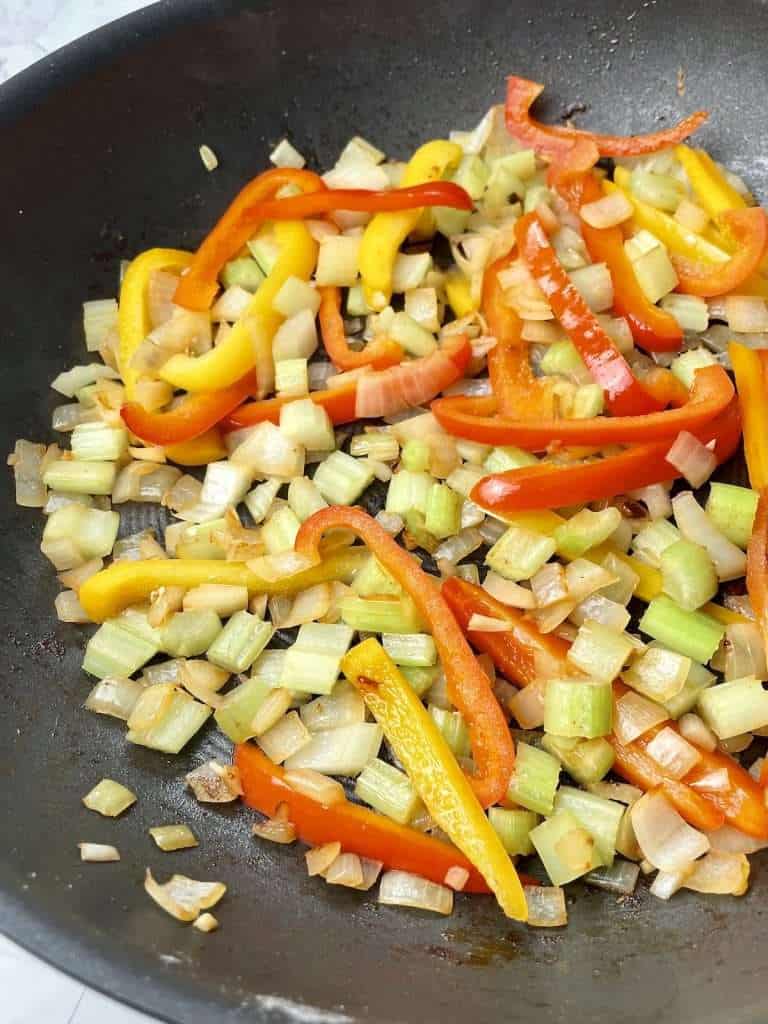 Cooking onions, celery, bell peppers, and garlic for Cajun smothered chicken