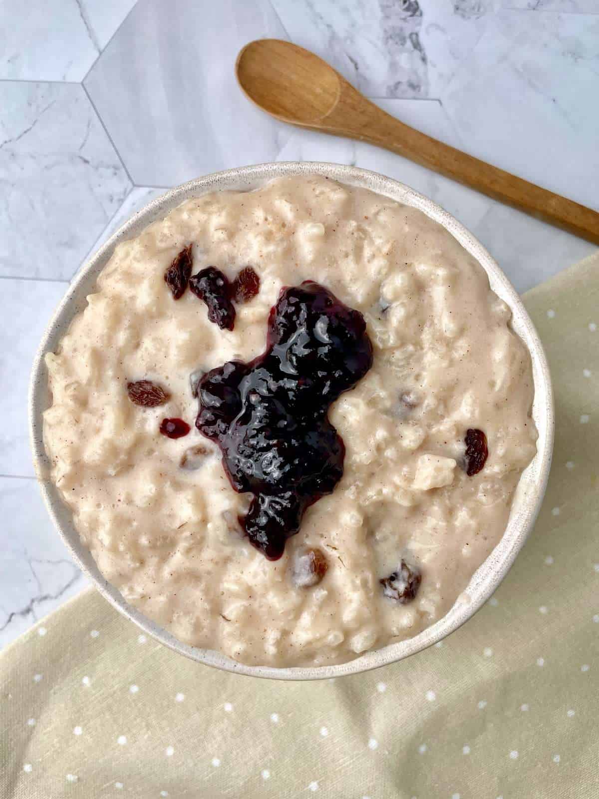 The essential ingredients for a creamy dairy-free rice pudding, including rice, dairy-free milk, maple syrup, spices, and vanilla, displayed on a countertop.