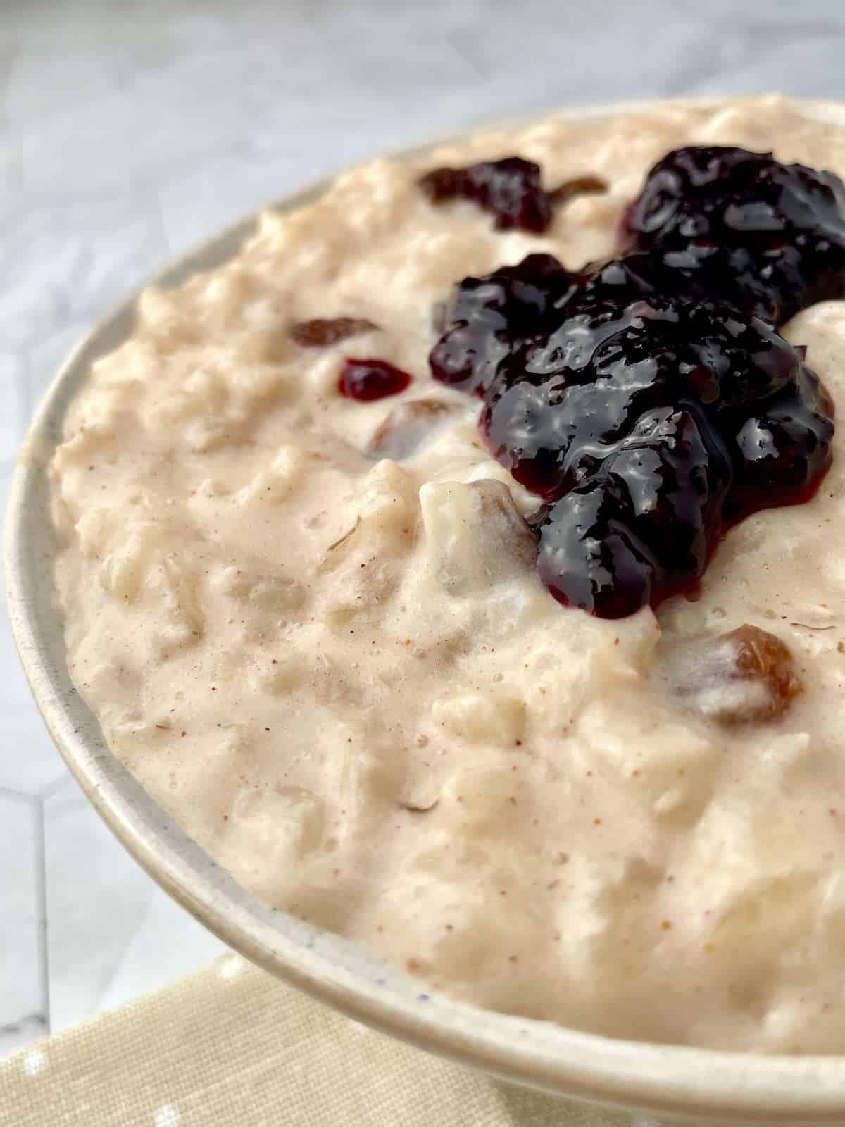 Vegan rice pudding served in a bowl with jam on the top.